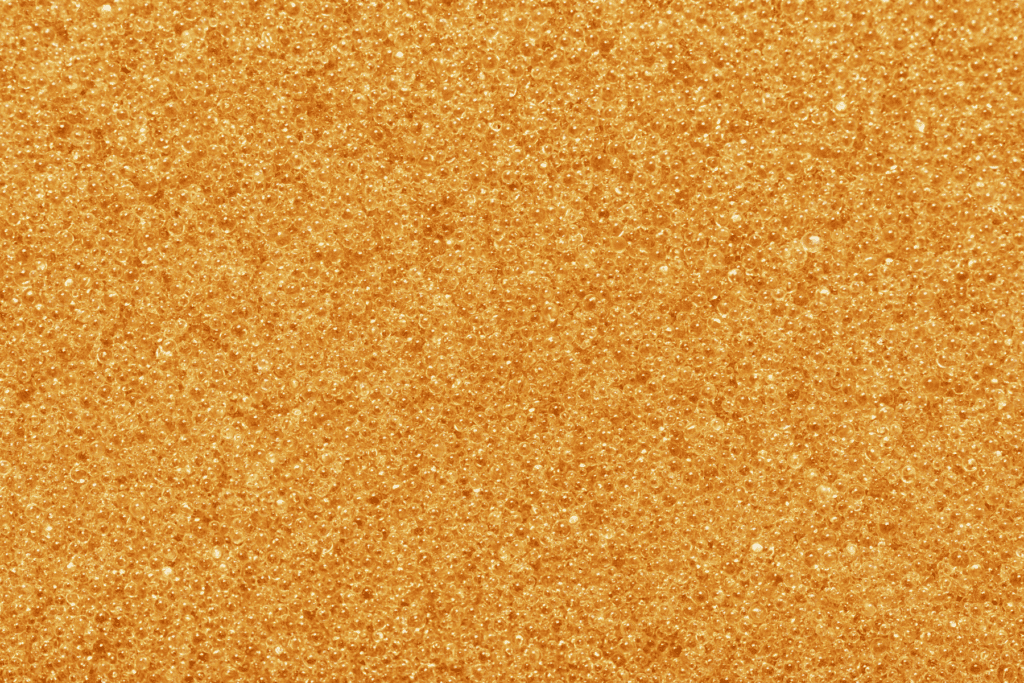 Close-up of many small orange beads clustered together, creating a textured and uniform surface, reminiscent of water softener resin replacement media.